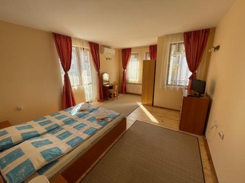 um quarto com uma cama e uma televisão em Family Hotel Biju em Tryavna