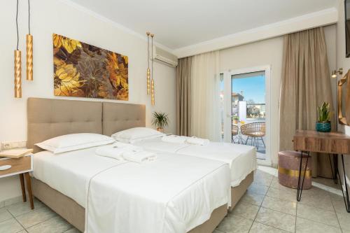a bedroom with a large white bed and a balcony at Ninemia Studios in Limenas