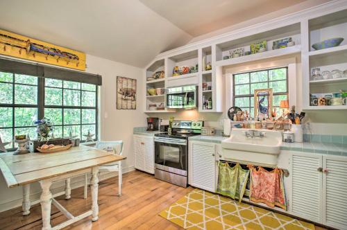 a kitchen with white cabinets and a table and a sink at Enchanting Whitney Cabin with Beach and Creek! in Diamondhead