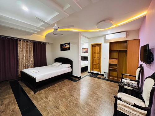a bedroom with a bed and a tv and a couch at AAKAS Hotel & Restaurant in Muzaffarabad