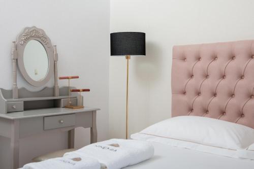 a bedroom with a pink headboard and a mirror at Ninemia Studios in Limenas