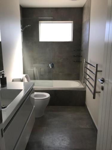 uma casa de banho com uma banheira, um WC e um lavatório. em Dunray Cottage - Welcome to Havelock North em Hastings