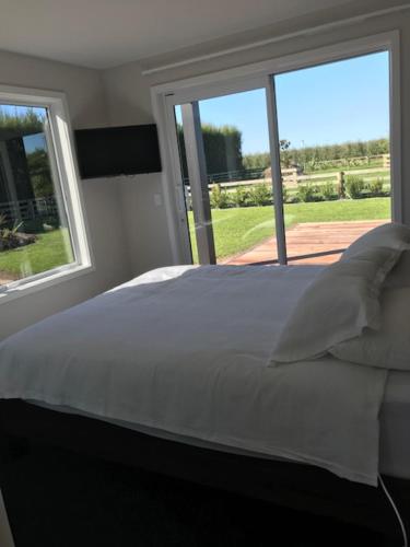 1 dormitorio con 1 cama blanca y 2 ventanas en Dunray Cottage - Welcome to Havelock North en Hastings