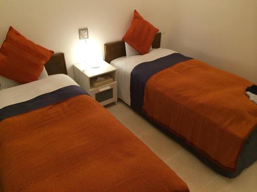 a room with two beds and a table with a lamp at Kyoto Travellers Inn in Kyoto