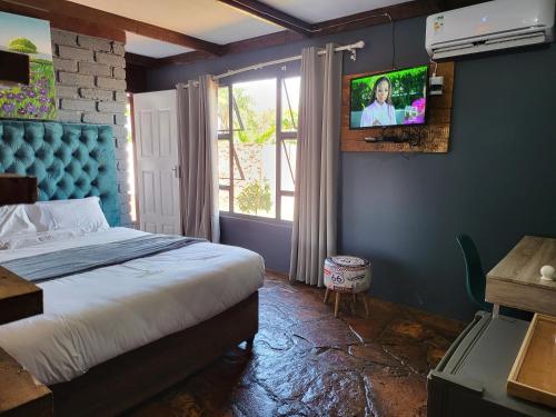 a bedroom with a bed and a tv on the wall at Shanduka Country Lodge in Thohoyandou