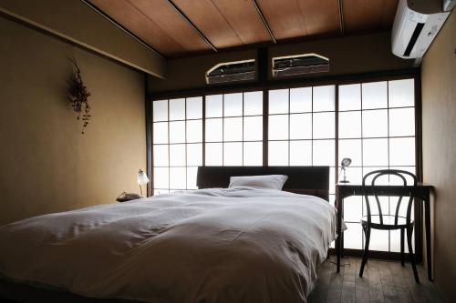a bedroom with a large bed and a large window at UNKNOWN KYOTO in Kyoto