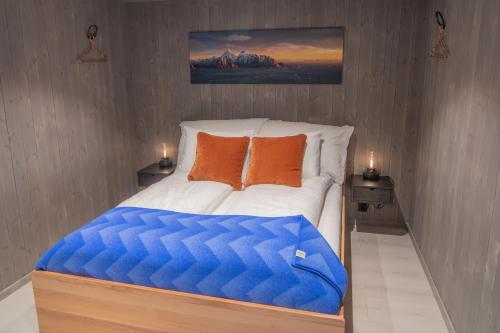 Schlafzimmer mit einem Bett mit blauen und orangefarbenen Kissen in der Unterkunft Været - Your Lofoten Basecamp in Henningsvær