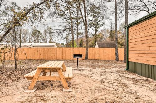 a wooden picnic table in a yard with a grill at Charming New Bern Log Cabin - Pets Welcome! in New Bern