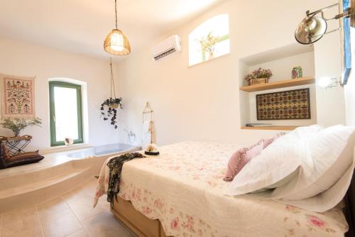a bedroom with a bed and a tub and windows at Mandarinies Boutique Residence in Kalymnos