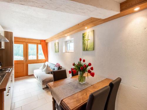 a living room with a dining room table with red flowers at Apartment in Sankt Gallenkirch near Ski Slopes in Sankt Gallenkirch
