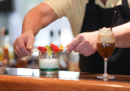 a bartender making a drink with strawberries and fruit at Hôtel Mount Venturi - Aix-En-Provence Sainte-Victoire - Bar & Restaurant & Padel in Rousset
