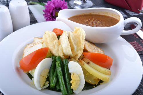 a plate of food with eggs and vegetables and a cup of soup at The Cube Hotel Malioboro, Azana Hotels Collection in Yogyakarta