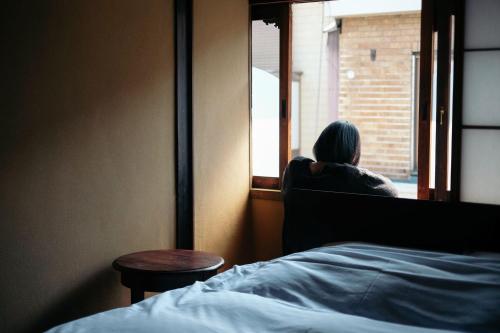 a woman sitting in a chair looking out of a window at UNKNOWN KYOTO in Kyoto