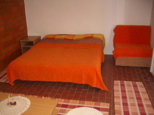 Apartment Dario في Gruda: غرفة نوم مع سرير وبطانية برتقالية