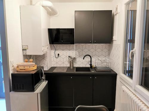 een kleine keuken met zwarte kasten en een wastafel bij Studio très chaleureux entièrement refait à neuf in Moulins