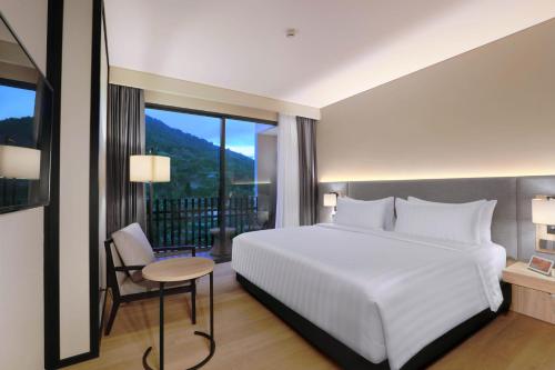 a bedroom with a white bed and a large window at Grand ASTON Puncak Hotel & Resort in Puncak