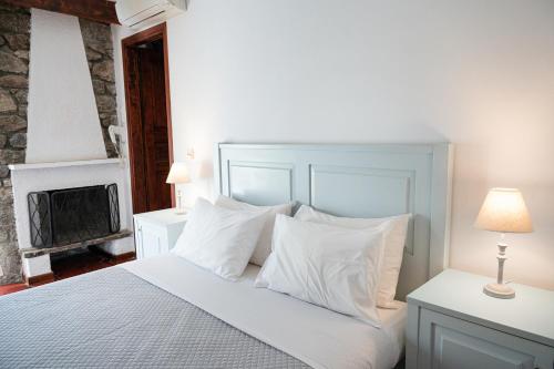 a bedroom with a bed with white pillows and a fireplace at Dionysos Hotel in Poros
