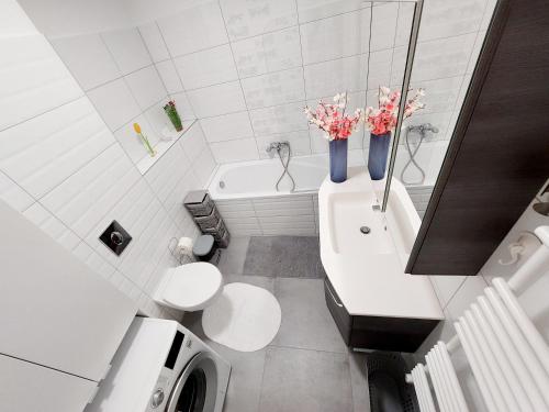 łazienka z 2 toaletami i wanną z kwiatami w obiekcie Juhar Apartman w mieście Kőszeg