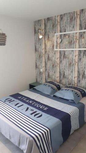 - un lit avec une couverture et des oreillers bleus et blancs dans l'établissement Étaules 10 min de la palmyre, à Étaules