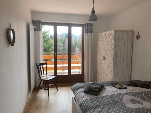 a bedroom with a bed and a chair and a window at La Jacinthe de Crans in Crans-Montana