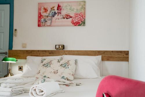 a bedroom with a white bed with a pink chair at Azra Apart & Otel in Gokceada Town