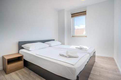 a bedroom with a bed with white sheets and a window at Blue Pearl Apartment in Cres