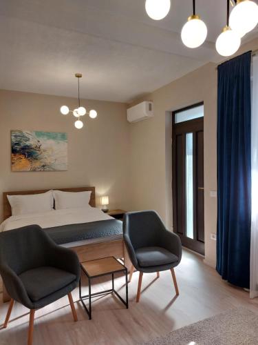 a bedroom with a bed and two chairs and a table at Mandarin Premium Apartments in Târgu-Mureş