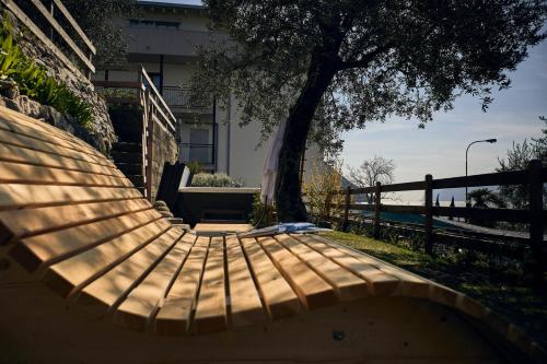 a wooden bench in front of a building with a tree at Hotel Paradiso Conca d'Oro in Nago-Torbole