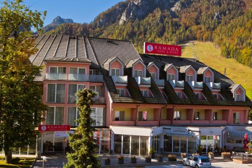 a large building with a mountain in the background at Ramada Hotel & Suites Kranjska Gora in Kranjska Gora