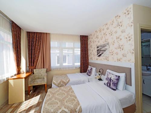 a hotel room with two beds and a chair at Nagehan Hotel Old City in Istanbul