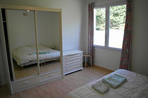 1 dormitorio con espejo, cama y ventana en Petite maison vendeenne cinq personnes pour des vacances reposantes, en Commequiers