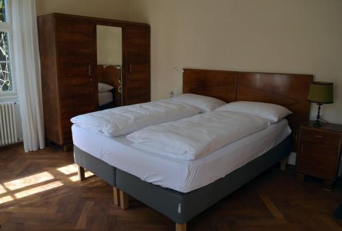 Bett mit einem Kopfteil aus Holz in einem Zimmer in der Unterkunft Villa Iolanda in Meran