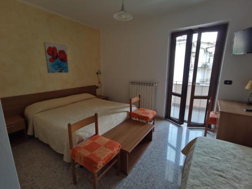 1 dormitorio con 2 camas, mesa y ventana en Hotel Edelweiss, en Laino Borgo