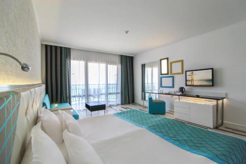 ゴールデン・サンズにあるSentido Marea Hotel - 24 hours Ultra All inclusive & Private Beachの白いベッドと大きな窓が備わるホテルルームです。
