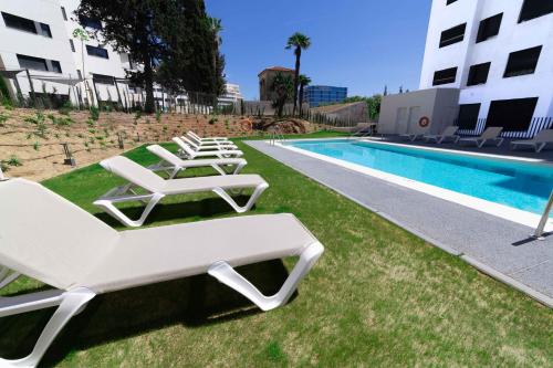 a row of lounge chairs next to a swimming pool at Aqua Apartments Bellamar, Marbella in Marbella
