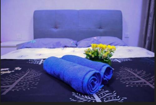 ein Bett mit zwei blauen Handtüchern und Blumen darauf in der Unterkunft HA2017, CYBERJAYA, Netflix, Wifi, Free Parking, 3030 in Cyberjaya