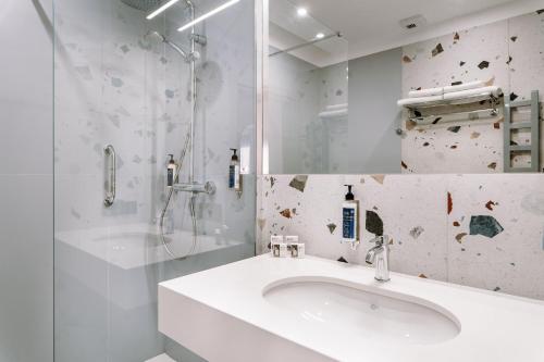 a white bathroom with a sink and a shower at Hotel ETER in Toruń