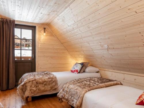 - 2 lits dans une chambre avec un mur en bois dans l'établissement SUNWEB - Les Chalets de L'Ecrin, à La Joue du Loup