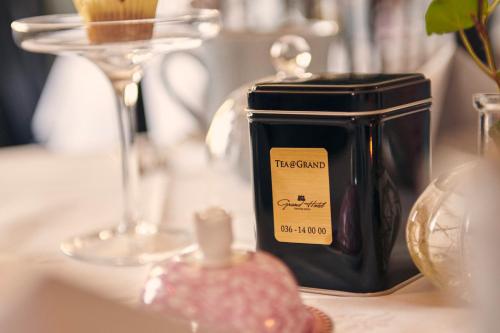 a black jar of teazos sitting on a table with glasses at Grand Hotel Jonkoping, BW Signature Collection in Jönköping