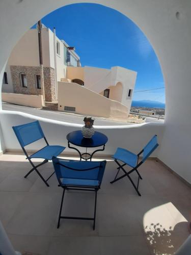 a table and chairs on a balcony with a window at Atlantida Spacious Flat in Fira
