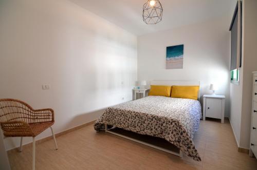 um quarto com uma cama com almofadas amarelas e uma cadeira em Agaete Paraíso em Agaete