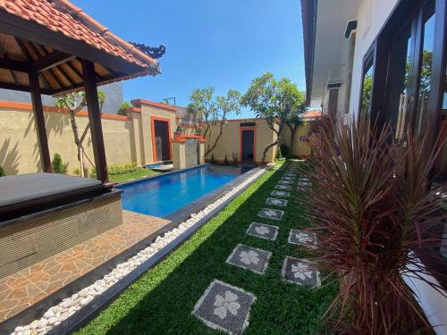 een achtertuin met een zwembad en groen gras bij Villa Margherita in Seminyak