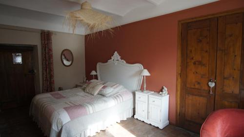 a bedroom with a white bed and a red wall at Le Mas Fraissinet in Saint-Jean-de-Valériscle