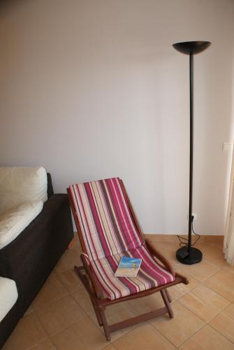 a book in a striped rocking chair next to a couch at Apartamento Felicidade in Almancil