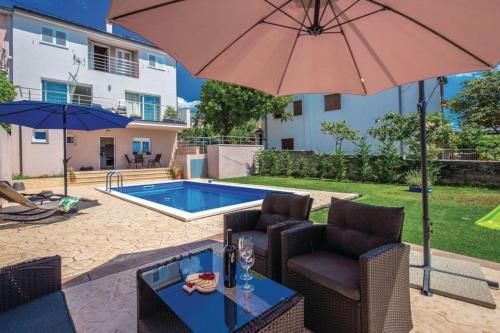 a patio with two chairs and an umbrella and a pool at House Lavander in Šmrika