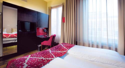 a hotel room with a bed and a desk and a television at Home Hotel Folketeateret in Oslo