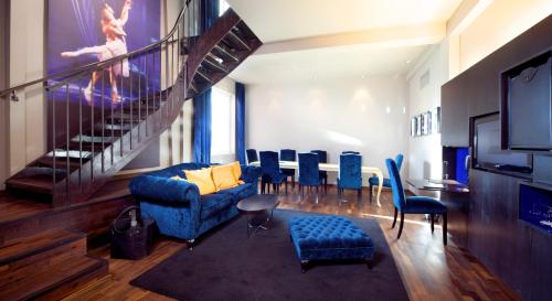 a living room with blue chairs and a staircase at Home Hotel Folketeateret in Oslo