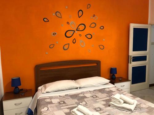 1 dormitorio con 1 cama con pared de color naranja en Rosy House, en Gaeta
