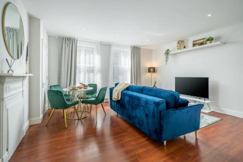 a living room with a blue couch and a table at TruStay Apartments London Brick Lane in London