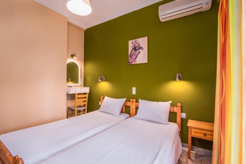 2 łóżka w pokoju z zieloną ścianą w obiekcie Southgate Apartments w mieście Agios Georgios